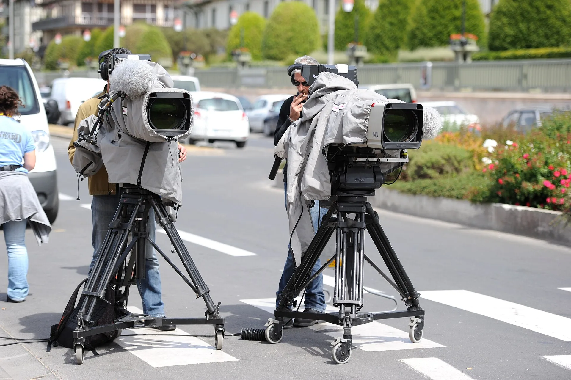 Two cameramen and their professional video camera on a tripod, protected with a rain cover, on Boulevard Eugène Cornuché in front of the Centre international de Deauville to cover the 37th G8 summit in Deauville, France. The crew belongs to video production company AMP VISUAL TV and the cameras are 